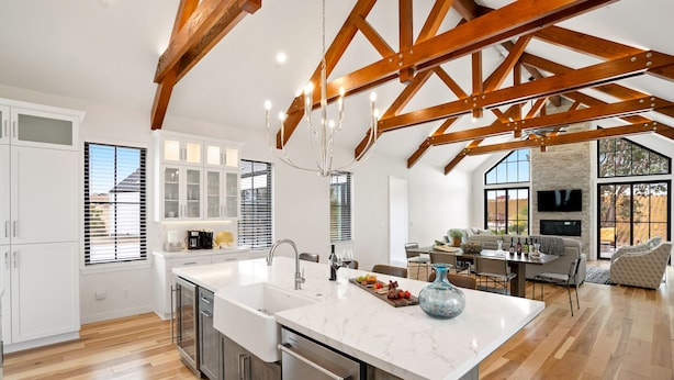 Una cocina amplia con una isla grande, vigas de madera y un comedor con sofá y mesa.