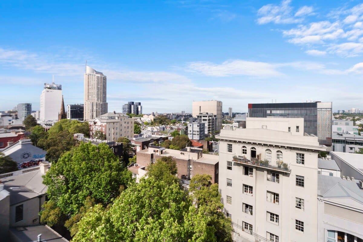 A cityscape with modern buildings, a mix of high-rise and low-rise structures, and a clear sky.