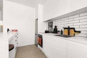 A modern kitchen with white cabinetry, a tiled backsplash, and a wooden cutting board on the countertop. - Best of city-suburbs living in trendy Darlinghurst (Darlinghurst)