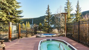 A swimming pool with a wooden deck, surrounded by a metal fence and trees. - Prime 3 Bedroom looking at Keystone Mtn House! (Keystone)