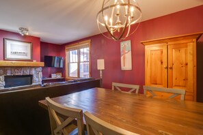 Een eethoek met een houten tafel en stoelen, een stenen open haard en een houten kast.