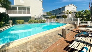 Una piscina con indicador de profundidad de 90 centímetros, rodeada de sillas de descanso y una terraza de madera.