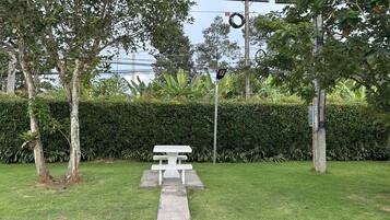 Un espacio cubierto de césped con una mesa de picnic blanca y una siega al fondo.