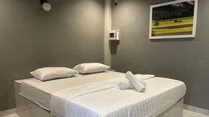 A neatly made bed with white linens and pillows, a small bedside table, and a wall-mounted air conditioner. - Baanmae Resort Thachana Suratthani (Tha Chana)