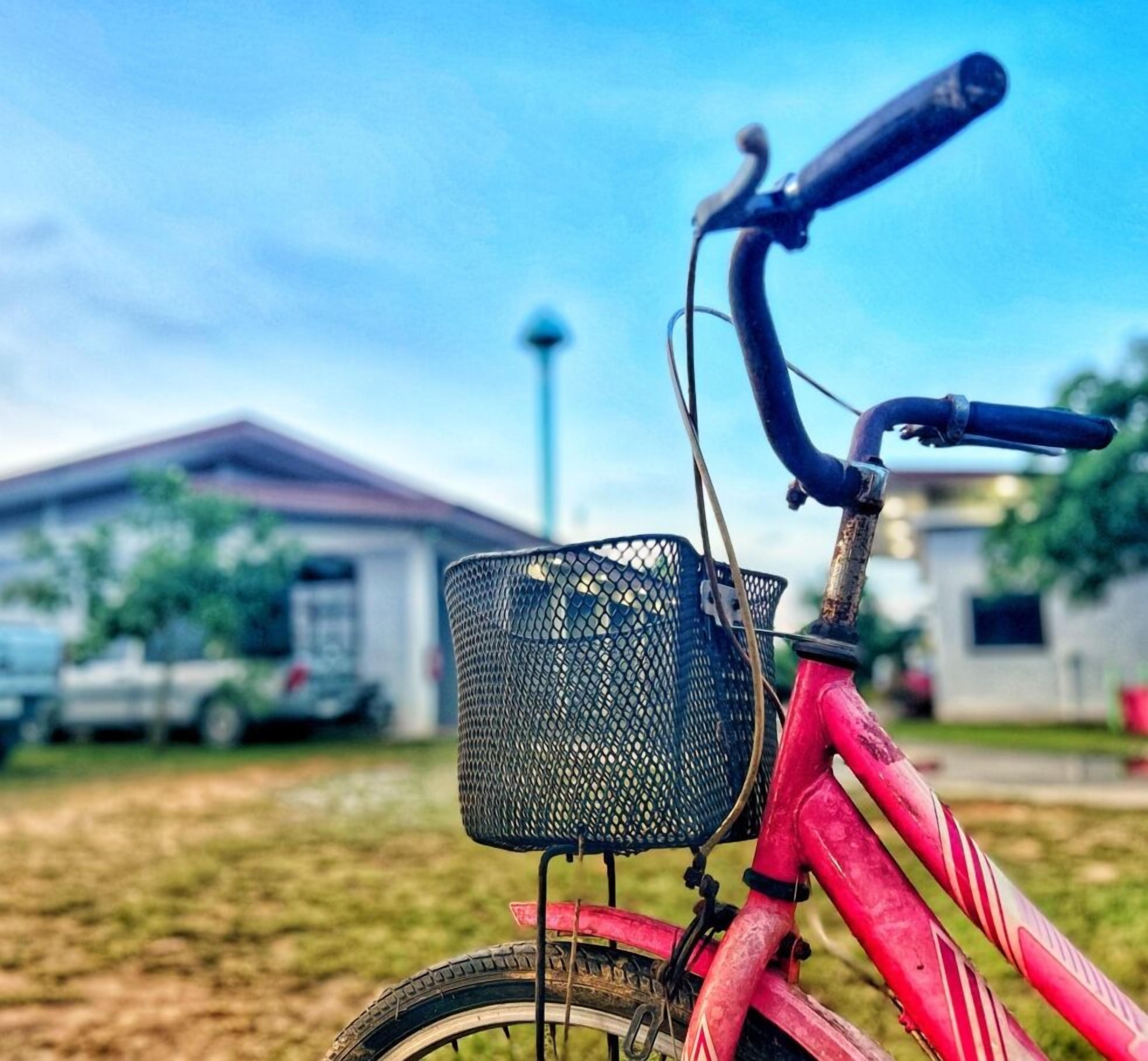 Una bicicleta roja con una canasta negra y manillar rojo.