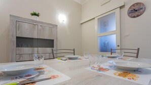 A dining table set with plates, glasses, and cutlery, with a wooden cabinet and a clock on the wall. - La Casa di Marygrace by Wonderful Italy (Turin)