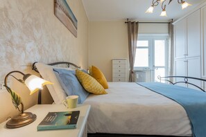 A neatly arranged bedroom with a bed, bedside table, lamp, and a window with curtains. - La Casa di Marygrace by Wonderful Italy (Turin)