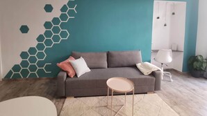 Un salon moderne avec un canapé gris, une petite table ronde et un motif hexagonal ornant le mur.