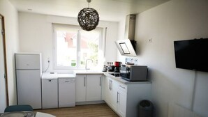 A compact kitchen with white cabinets, a sink, a microwave, and a television. - T1 - Studio Confortable Wissant (Wissant)