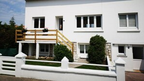 A two-story white building with a wooden staircase, a small garden, and a white fence. - T1 - Studio Confortable Wissant (Wissant)