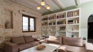 Ein Wohnzimmer mit einer Steinswand, einem beigen Sofa, einem weißen Couchtisch und einem Bücherregal voller Bücher.