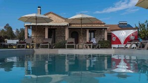 Ein Haus mit Swimmingpool, Sitzgelegenheiten im Freien und einem geparkten Auto.