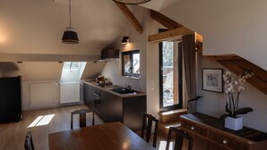 Een moderne keuken met een groot eiland, een eethoek met een houten tafel, en uitzicht op het landschap door een raam.
