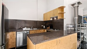 Una cocina moderna con armarios de madera, lavavajillas de acero inoxidable y horno empotrado.