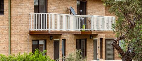 A two-story brick building with a balcony, windows, and a satellite dish.