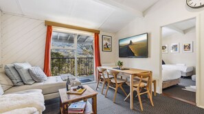 Una habitación acogedora con sofá, una mesa de comedor con sillas, cama y un gran ventanal con vistas.