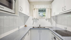 Een moderne keuken met witte kasten, een roestvrijstalen spoelbak en een ingebouwde kookplaat.