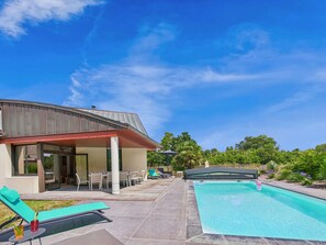 Una casa moderna con piscina, area salotto esterna e patio coperto.