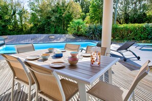 An outdoor dining area with a pool in the background. - Garden and pool - 1km from beach- For 8 (Fouesnant)