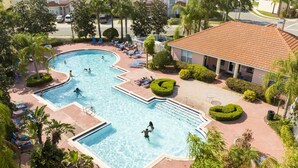 A large outdoor swimming pool with multiple lanes, surrounded by palm trees and lounge chairs.