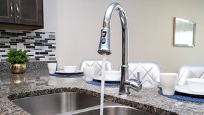 A kitchen with a stainless steel sink, a faucet, and a tiled backsplash.