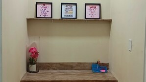 A shelf with three framed motivational posters, a potted plant, and a blue pencil holder with stationery. - paratemporada (Belém)