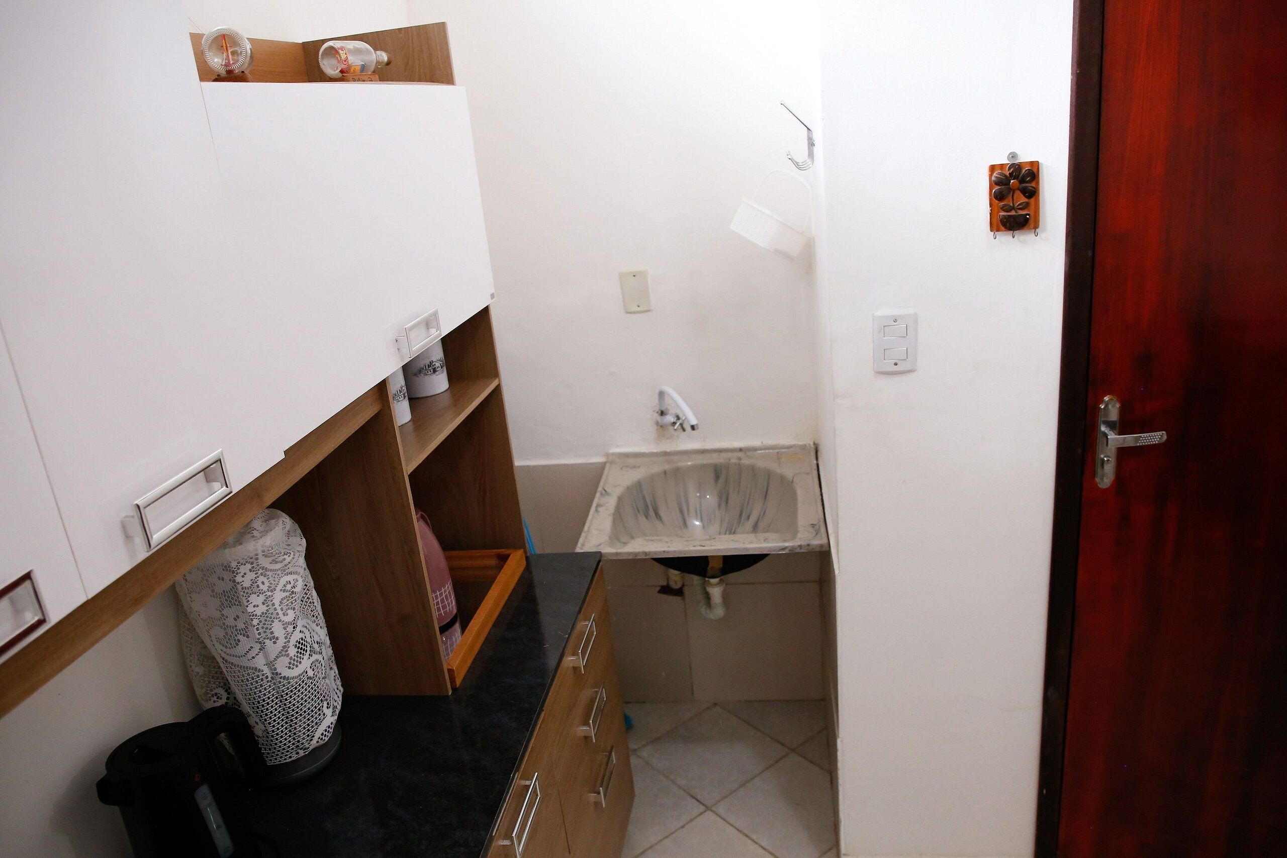 Un baño pequeño con lavamanos, espejo y repisa de madera.