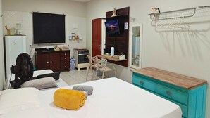 A compact hotel room with a bed, a desk, a chair, a TV, a wardrobe, and a small kitchenette. - paratemporada (Belém)