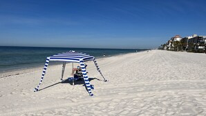 Une plage avec un parasol rayé et une chaise.