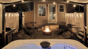 A hot tub with a fire feature, surrounded by outdoor seating and string lights. - The Lambertville Haven (Lambertville)