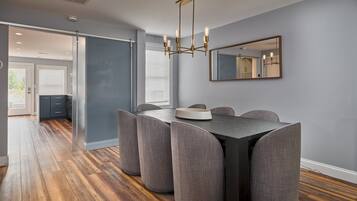 A dining area with a dark table, grey upholstered chairs, and a modern chandelier.