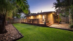 Ein modernes Haus mit Terrasse, Holzdeck und einem gepflegten Rasen.