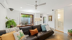 Ein modernes Wohnzimmer mit einer schwarzen Ledersofa, einem Esstisch und einem Deckenventilator.