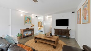 Ein modernes Wohnzimmer mit einer Ledersofa, einem Holztisch und einem an der Wand befestigten Fernseher.