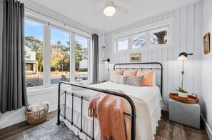 Une chambre à coucher avec un lit, une fenêtre, une table de chevet et une lampe.