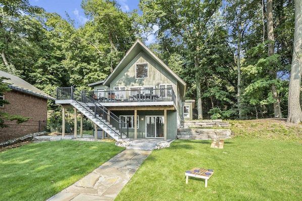A two-story house with a balcony, a stone staircase, and a small deck.