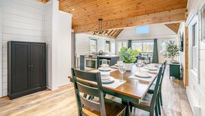 A spacious kitchen with modern appliances, a dining area with a wooden table and chairs, and a view of the outdoors. - Park Place: Luxury Riverfront Home, Walk to Lake Michigan & Chain Ferry, Deck (Saugatuck)