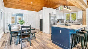 A spacious kitchen with a central island, wooden ceiling, and white cabinetry. - Park Place: Luxury Riverfront Home, Walk to Lake Michigan & Chain Ferry, Deck (Saugatuck)