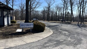 A residential street with a 'SECURITY' sign, houses, and leafless trees.