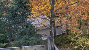 A wooden fence with a view of a residential area, including houses and trees with autumn foliage.