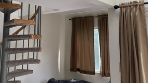A room with a bunk bed, a window with curtains, and a skylight.