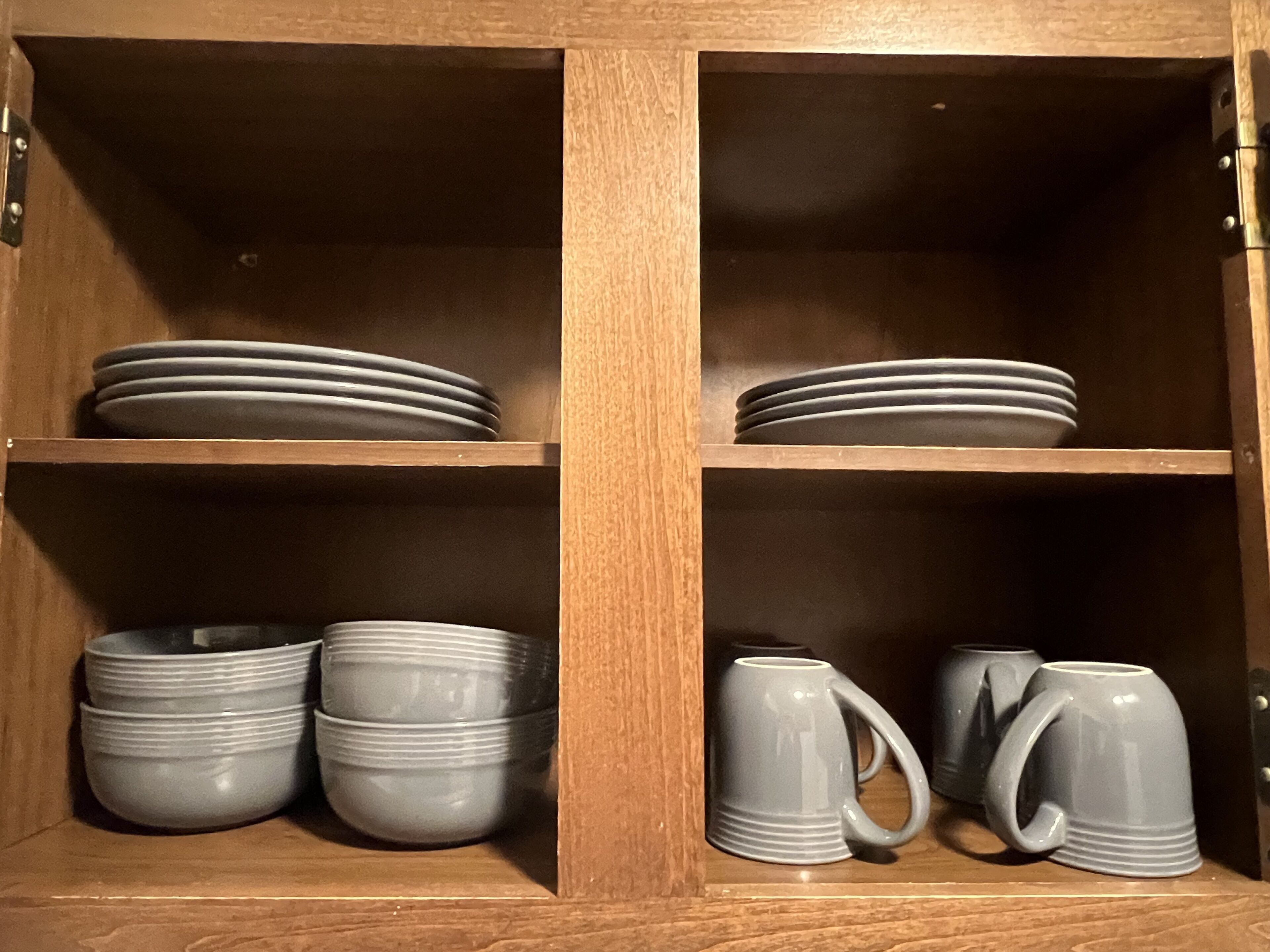Un armario de madera con estantes que contienen platos y tazones.