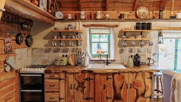 A rustic kitchen with wooden cabinets, a built-in oven, and various kitchen utensils and appliances.