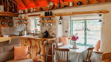 A rustic kitchen with wooden shelves, a dining area with a table and chairs, and a cozy seating area with a sofa.