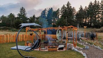 An outdoor patio with a grill, seating, and a swing chair.