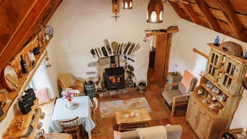 A cozy, rustic interior with a stone fireplace, wooden furniture, and a high ceiling with exposed beams.