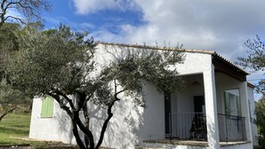Un petit bâtiment blanc doté d’un balcon, entouré d’arbres.
