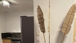Une cuisine moderne équipée d’un lave-vaisselle, d’une chaise en bois et d’un vase contenant des plantes séchées, posé sur le sol.
