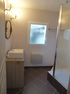 Bathroom features a pedestal sink, decorative mirror, and glass shower enclosure.