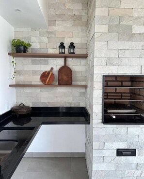 Una cocina moderna con salpicadero de piedra, estantes de madera y una parrilla empotrada.